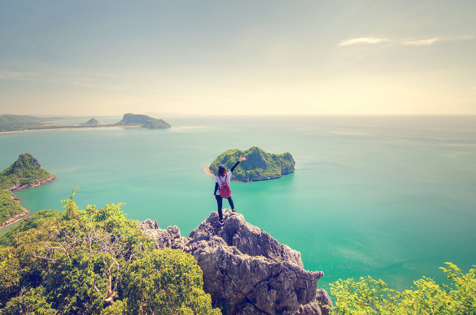 Freedom traveler woman standing with raised arms on the top of mountain and enjoy the beautiful of seascape, Travel and Freedom concept, Retro filter effect.